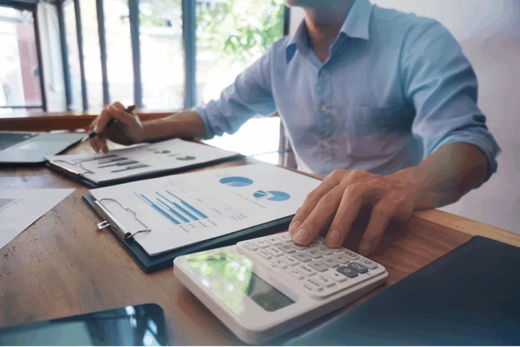 una persona usando informes y una calculadora para conocer el precio de las Letras del Tesoro y ver si es una buena inversión